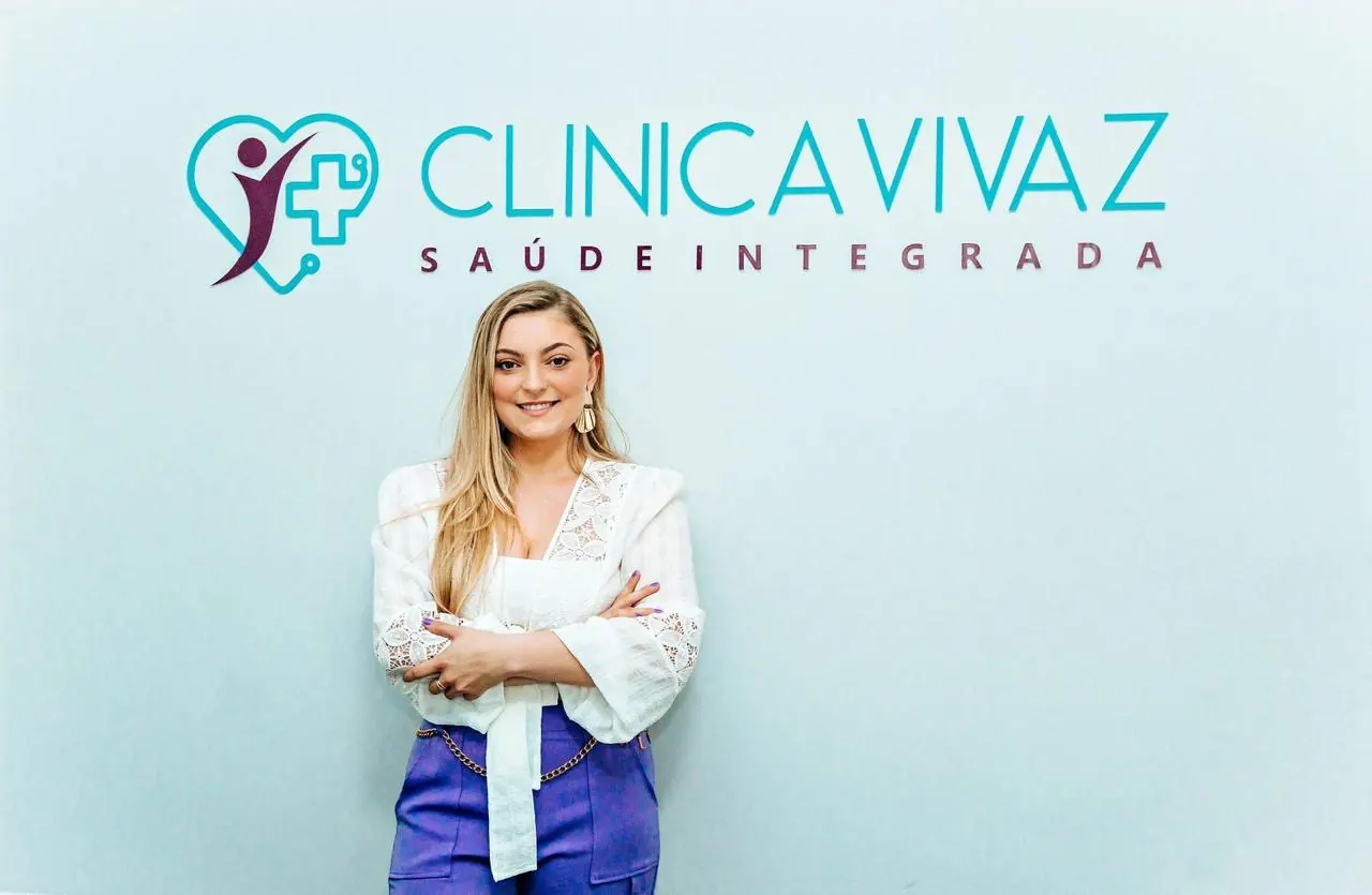 Fernanda Ferrari Godoi, fisioterapeuta, diante do logotipo da Clínica Vivaz